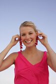 Woman holding red currant bunches near her ears, smiling