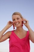 Blonde woman holding currant branches to her ears, smiling