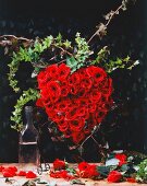 Gesteck aus roten Rosen in Form eines Herzens.