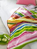 Close-up of bed sheet with colourful stripes lying on a bed