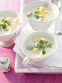 Three bowl of asparagus soup with cream and dumplings on plate