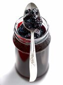 Glass with blackberry and elderberry jam with spoon on it