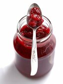 Glass jar of cherry and kumquats with spoon on it