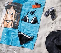 Badehandtuch im Sand mit Bikini Sonnenbrille, Schuhe + Foto