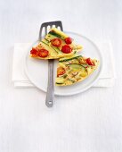 Two pieces of vegetable frittata on plate with spatula