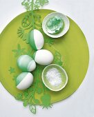 Vier halb gefärbte Eier und eine kaputte grüne Schale auf Teller