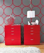 Two red lacquer chest of drawers with candle stand and vase against gray background