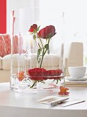 Glasvase mit Rosen und Kerzenleuchter aus Glas