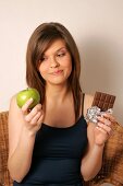 Woman with long hair holding green apple and chocolate