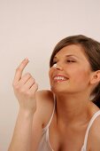 Side view of Magdalena woman with brown hair having cream on her nose and finger, smiling