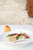 Terrine of duck, goose foie grass, pigeon breast with plum vinegar in white dish