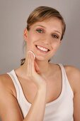 Portrait of beautiful blonde woman cleansing face with pad, smiling