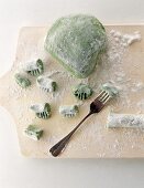 Pieces of soft dough being shaped with fork on wooden board