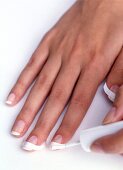 Close-up of woman applying white nail paint on one hand