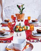 Exotische Tischdekoration, Gläser in rot und orange, Früchte auf Blatt