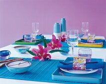 Table with blue dishes, glasses and flowers