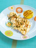 Grilled chicken breast with capers, pine nuts and grilled lemon served on plate