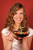 Pretty woman holding bowl of salad and fork, smiling