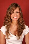 Beautiful woman with long curly hair wearing white top standing and laughing