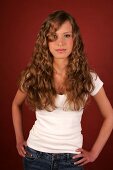 Beautiful woman with long curly hair wearing white top standing and laughing
