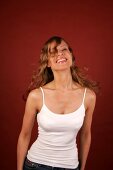 Portrait of beautiful woman with long curly hair wearing white top standing and laughing