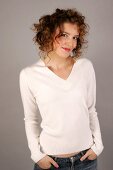 Portrait of beautiful woman with curly hair wearing white sweater, smiling widely