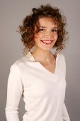 Portrait of beautiful woman with curly hair wearing white sweater, smiling widely