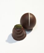 Two chocolates one garnished with pistachio on white background