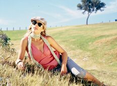 Beautiful woman wearing beret and sunglasses relaxing on meadow
