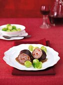 Rolled slice of beef with pepper filling and Brussels sprouts on plate