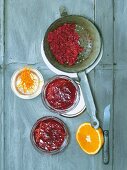 Currant and orange jelly in sieve with halved orange and orange zest