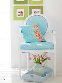 Wooden chair with blue polka dot cover, pillow, tray and tulips in milk jug