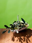 Close-up of bowl with olive oil and olive branch kept on wooden table