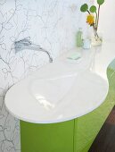 Weißes Waschbecken in Blattform auf grünem Waschtisch, Wasserhahn