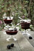 Three dessert glasses with blackberry dessert and whole blackberries