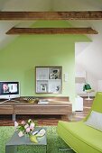 Room with green sofa, table, sideboard, television, sloping ceiling and roof beam