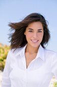 Portrait of beautiful brunette woman wearing white blouse, smiling