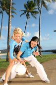 Two women playing ball under palm trees in a park