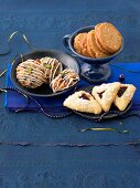 Almond cookies with pistachios and spiced biscuits in bowl and triangular cookies on plate