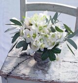 White hellebores in flower vase on wooden chair