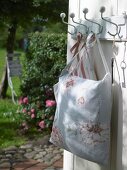 Pillow with rose pattern hanging on coat hook outdoors