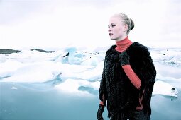 blonde Frau vor Eisschollen, trägt Pelzponcho, Blick nach links.X