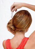 Frau steckt Haarknoten mit Nadeln fest, Step 3 zur Hochsteckfrisur