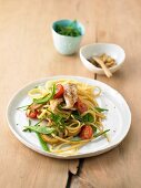 Spaghetti with vegetables, chicken, cherry tomatoes and sugar snap peas on plate