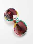 Pink sunglasses with patterned border on white background