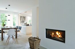 Basket in front of fireplace in open-plan interior with white walls