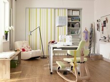 Sewing machine on table in front of fitted wardrobe with striped door on sewing room