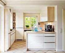 Helle Einbauküche mit Holz-Arbeitsplatte, Sprossenfenster und gefliestem Boden