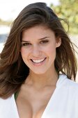 Portrait of beautiful dark haired woman wearing white zipper jacket smiling, close-up