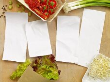 Four blank pieces of paper surrounded by salad ingredients